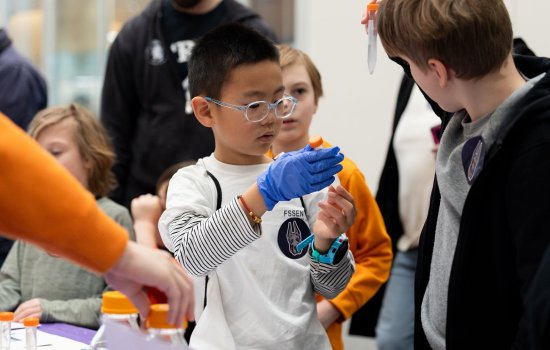 A young student holds up a beaker at STEM and Earth Sciences Family Day.