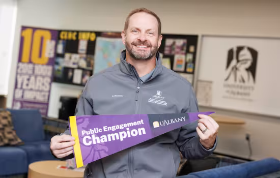 Mike Baumgardner holds up a Public Engagement Champion pennant.