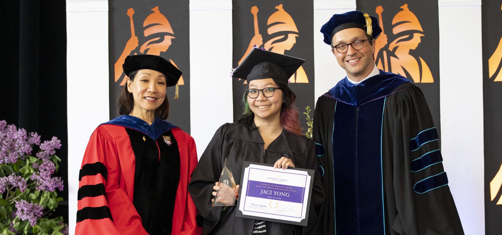 2023 Lavender Award Recipient posting with distinguished UAlbany faculty in full graduation regalia