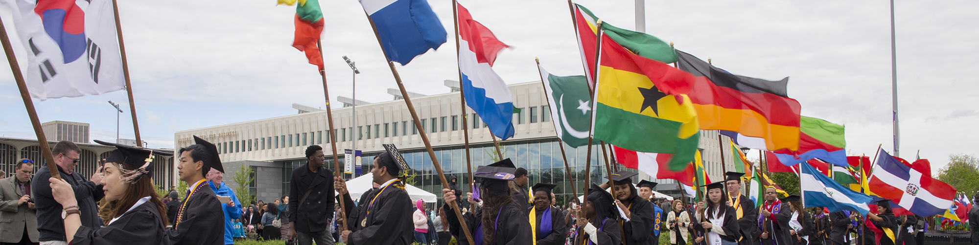 Students holding flags from their countries at commencement.
