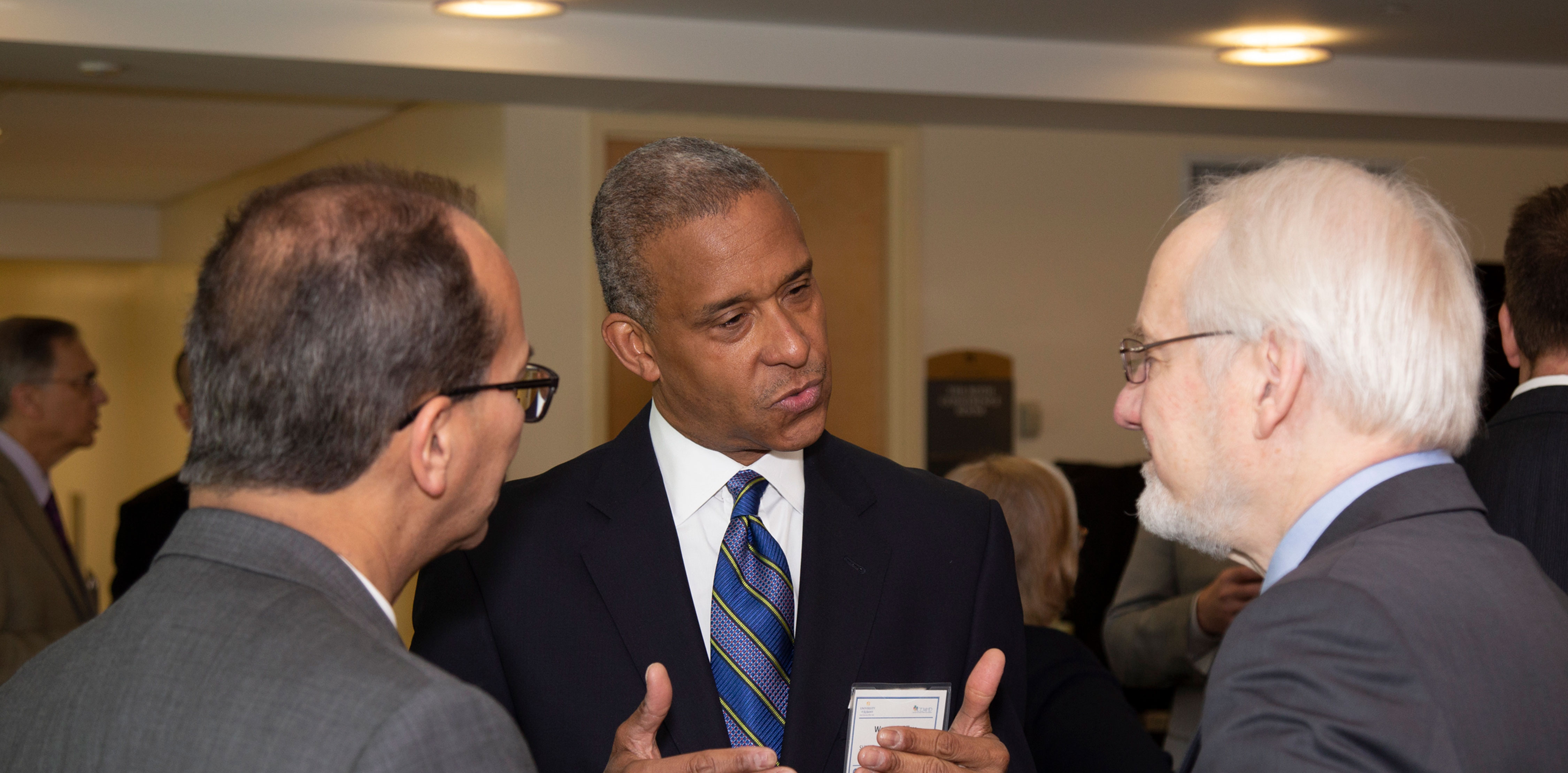 Three researchers converse at a CEMHD event.