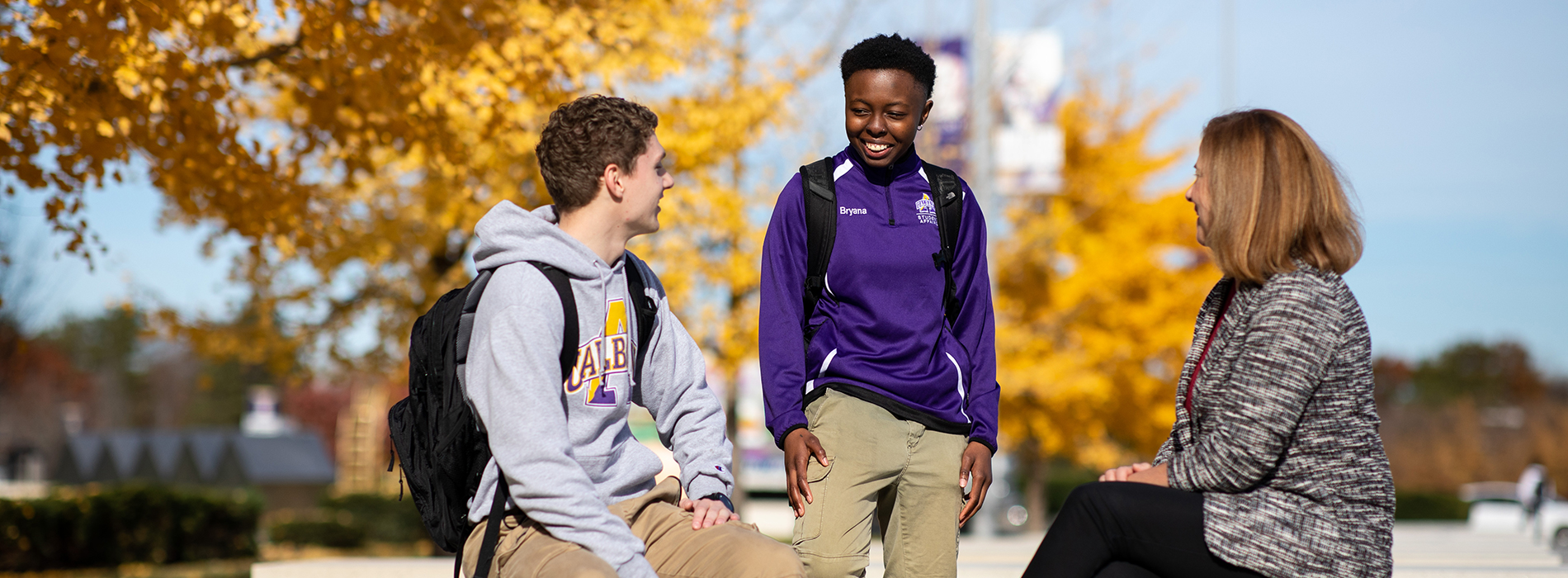 Three people having a conversation on the UAlbany Entry Plaza.