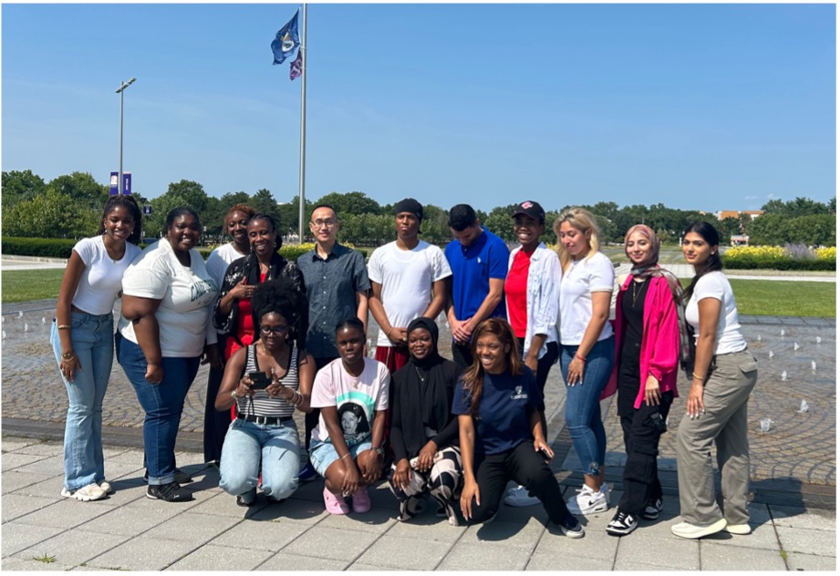 Fifteen undergraduate students participating in SUNY Downstate Health Sciences University's Summer Program in Translational Disparities and Community Engaged Research (SPRINTER) pose for a photo outdoors on UAlbany's campus.