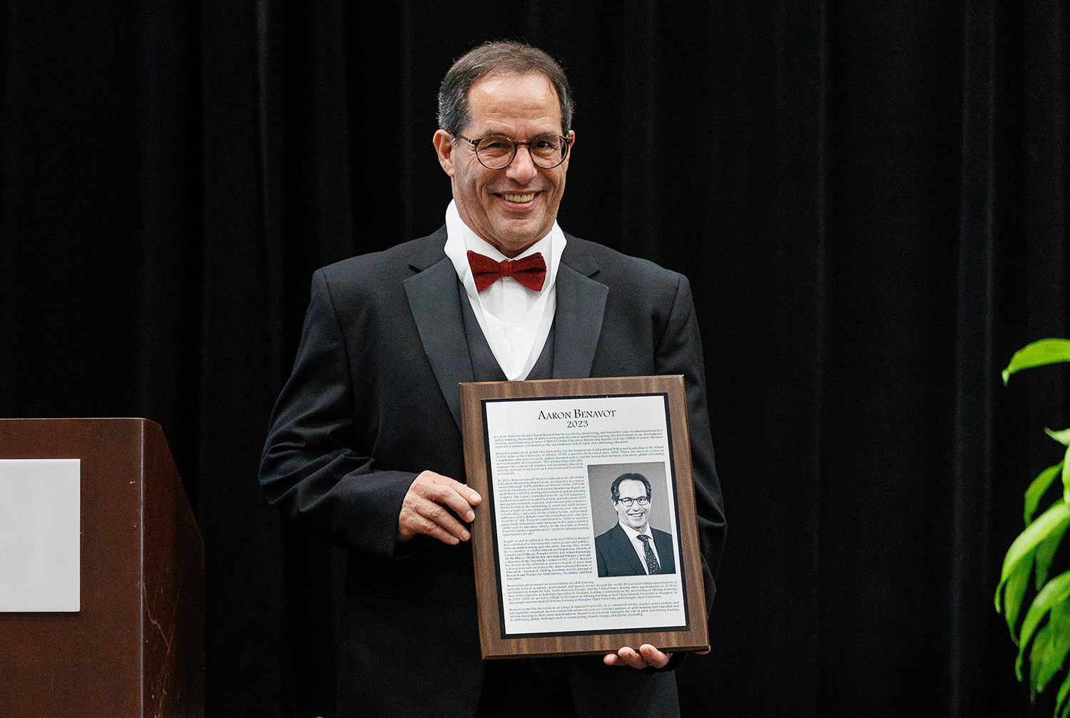 man in tuxedo holding plaque