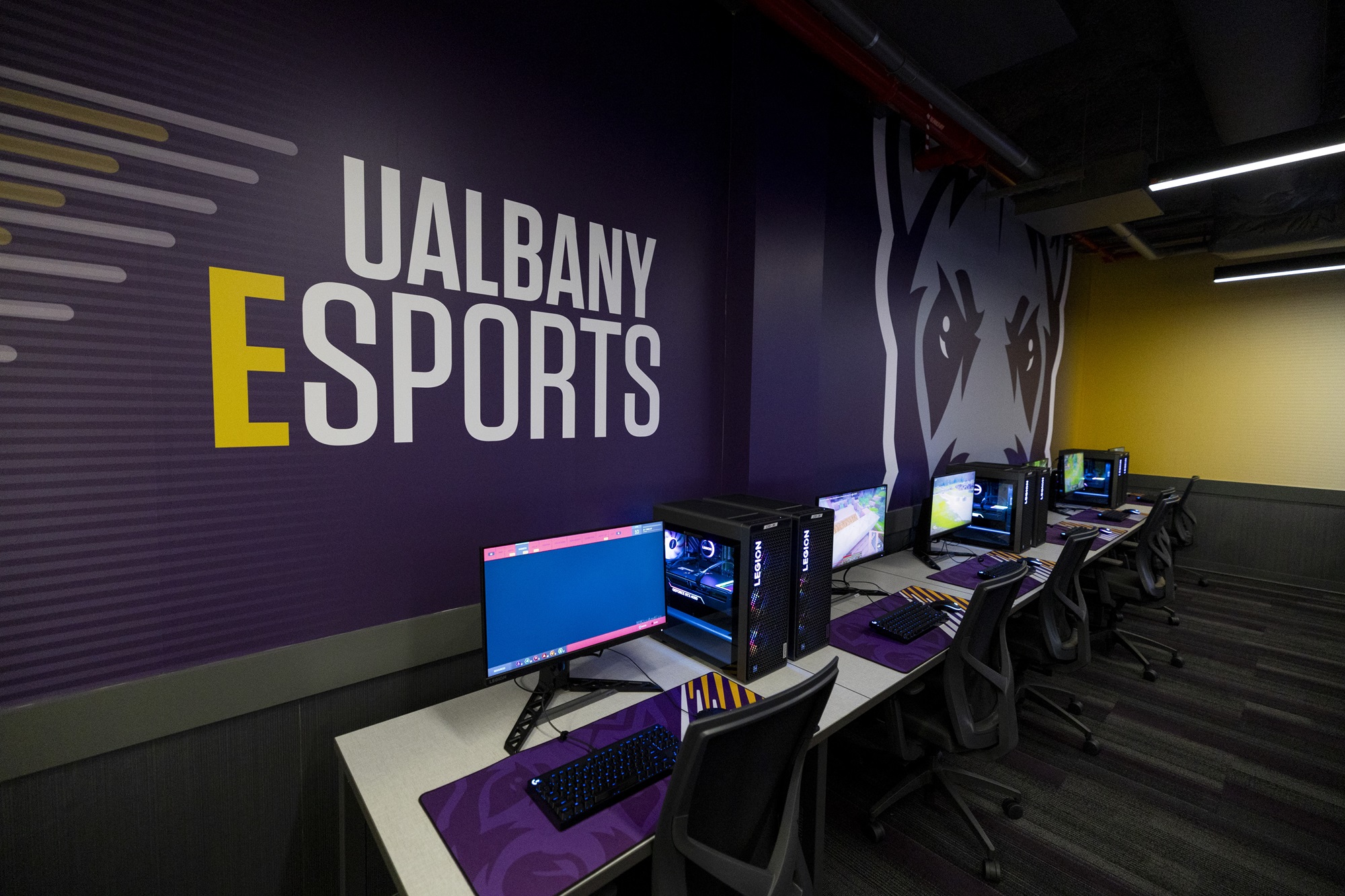 Lenovo Legion T7 gaming PCs in front of a UAlbany Esports graphic.