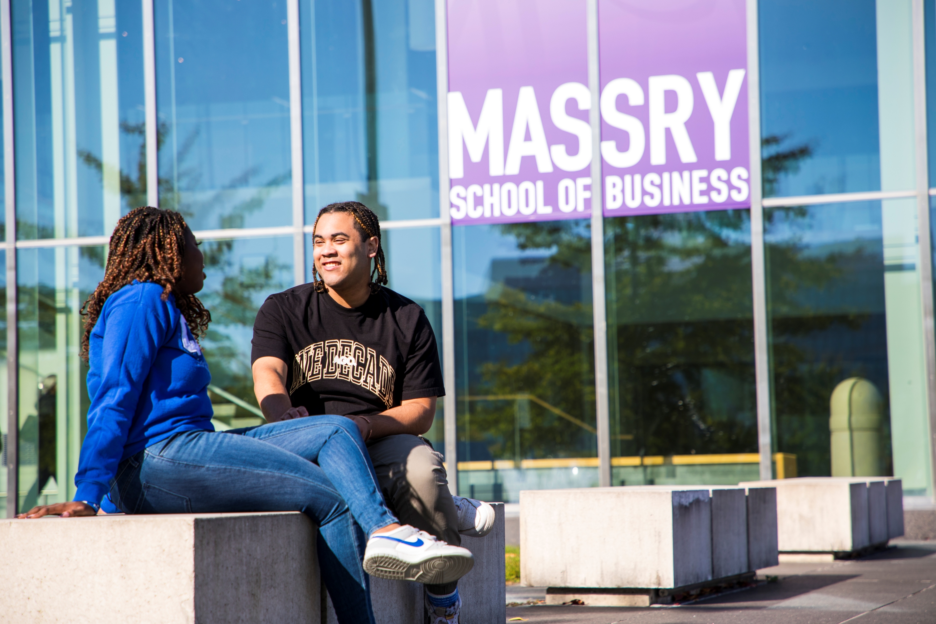 Tow students sit outside of UAlbany's Massry School of Business building. (Photo by Patrick Dodson)