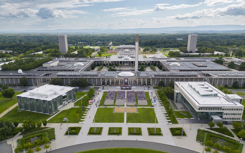 An aerial photo of the broad green entry plaza to UAlbany's campus with its iconic campus Podium in the background.