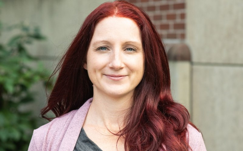 A smiling woman with red hair and a pink sweater.