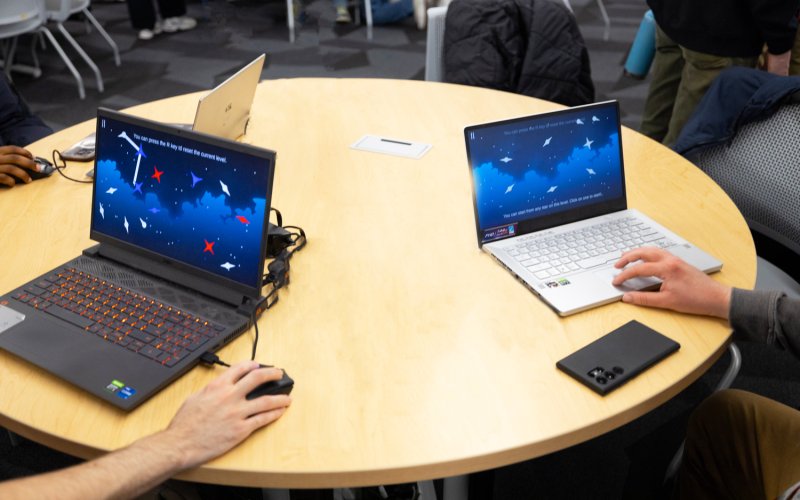 Students test games from laptops in a conference room at ETEC.