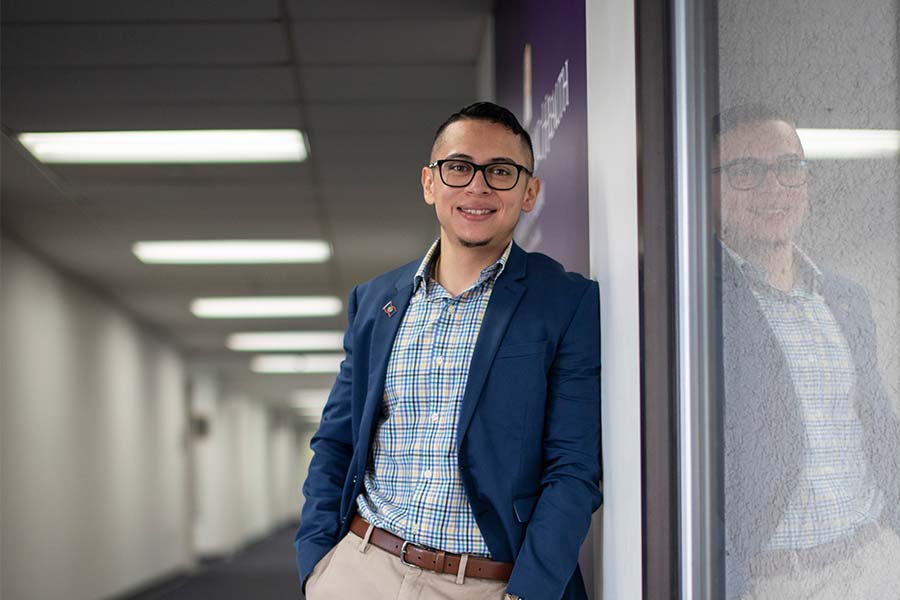 Andrei in a blue blazer standing in a hallway in the School of Public Health.