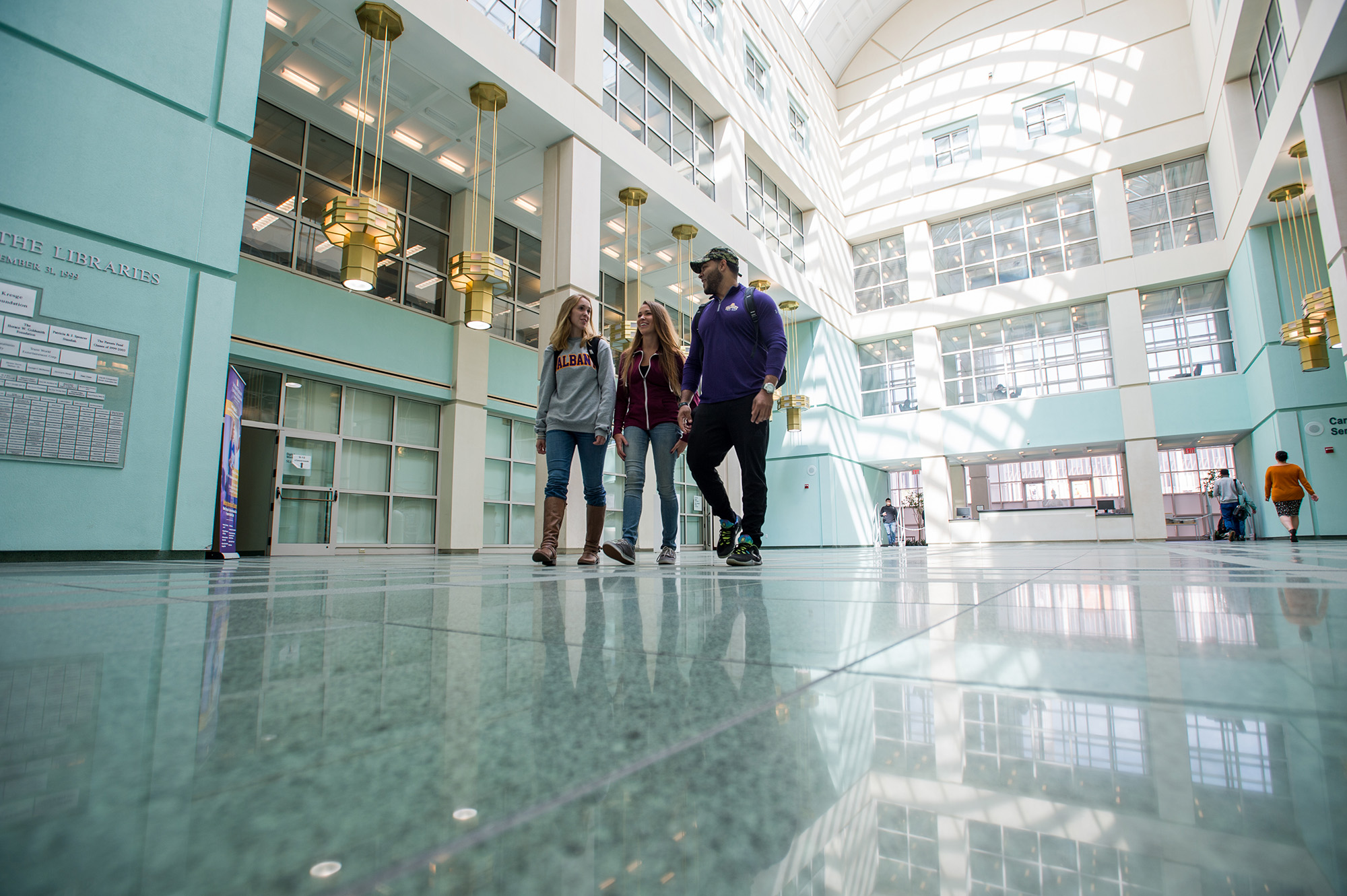 Three students walking in the UAlbany Science Library atrium.