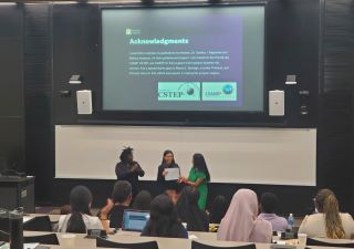 Maria De Sousa presenting with two other students in a lecture hall