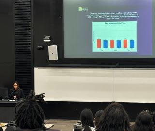 Maria De Sousa presenting at a podium in front of a class