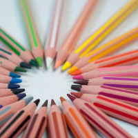 Colored pencils are arranged in a circle on a white table