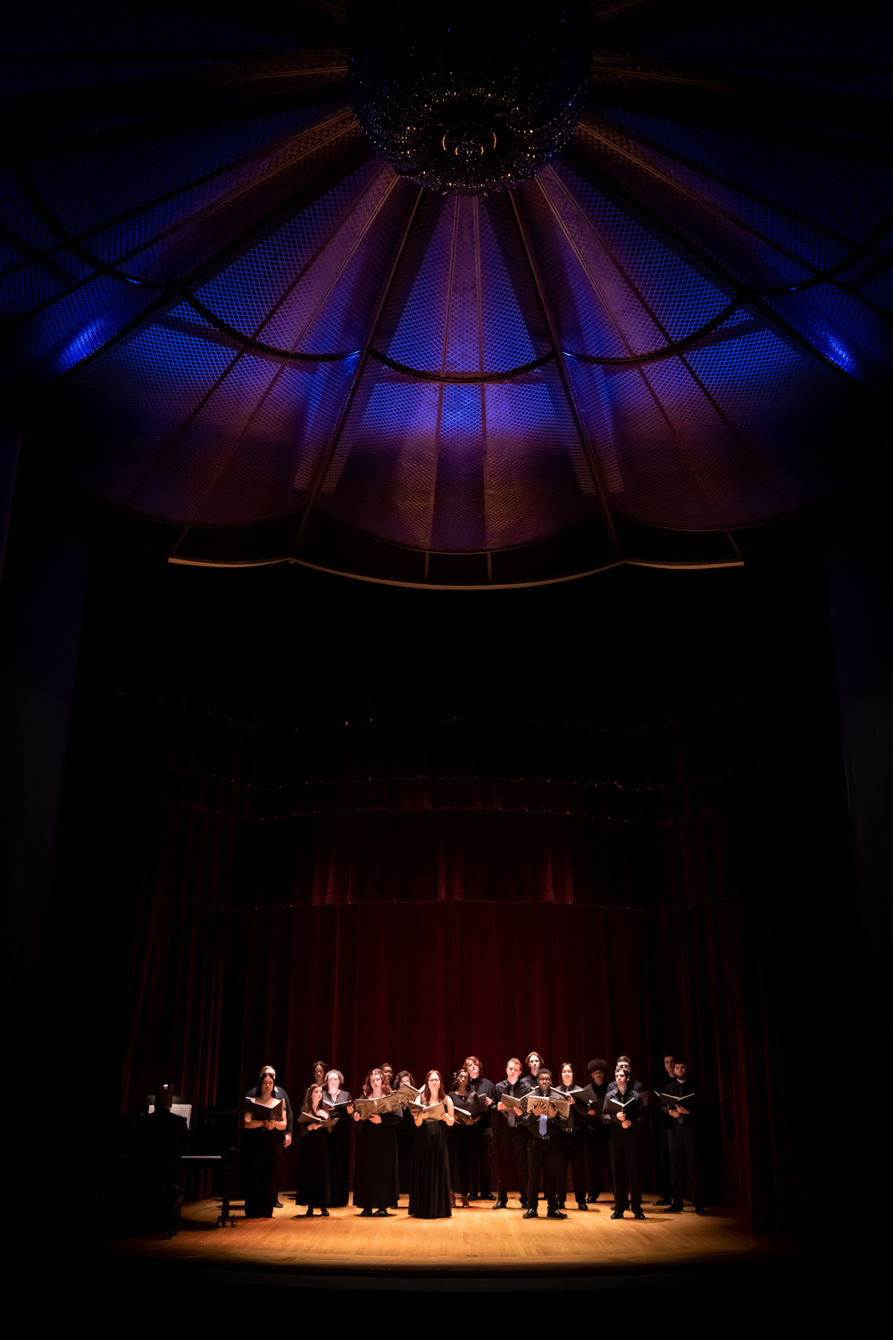 A group of students on stage during a singing performance in the UAlbany Performing Arts Center.