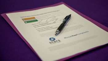 a document lies on a purple folder with a pen resting on it.