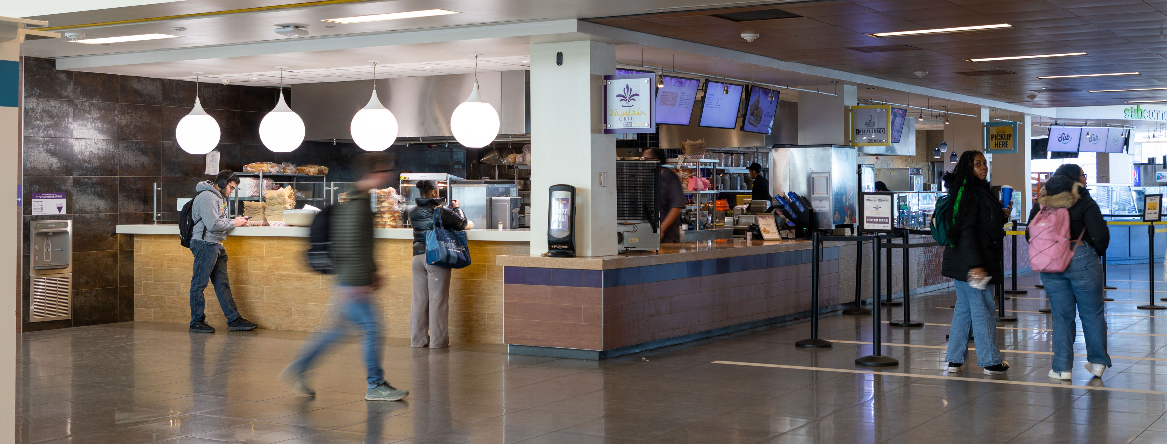 Students walk by and stand in line in front of a retail dining venue in UAlbany's Campus Center.