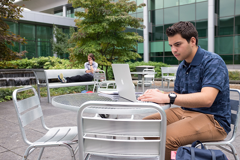 A student studying on a laptop in the UAlbany Life Sciences courtyard.