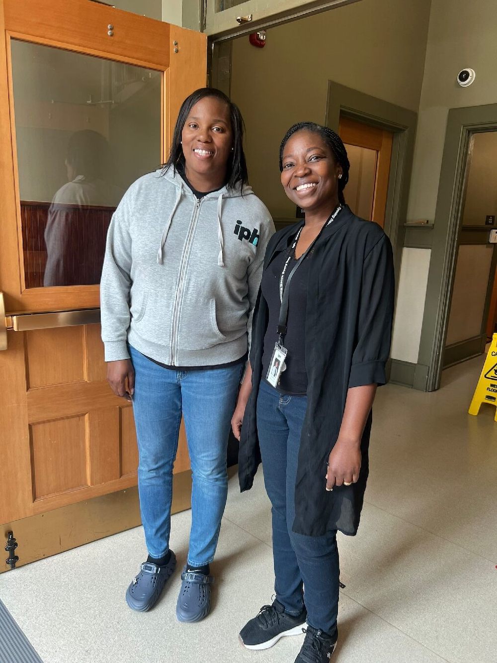 Two women smile and stand in a doorway posing for a picture