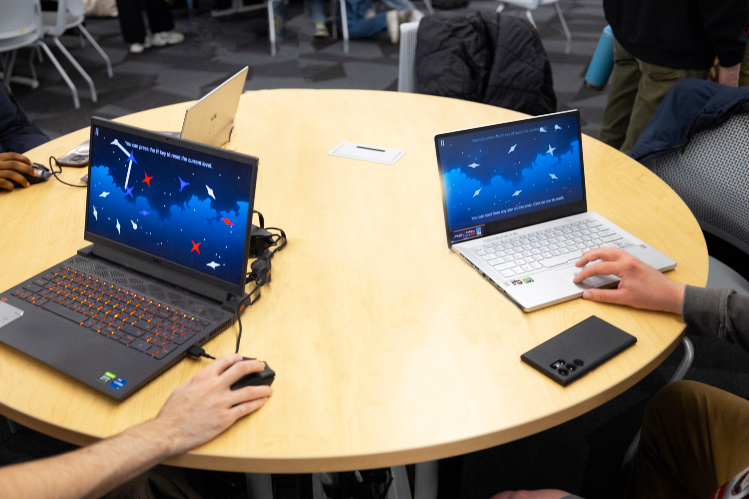 Two students working on game design on laptops.