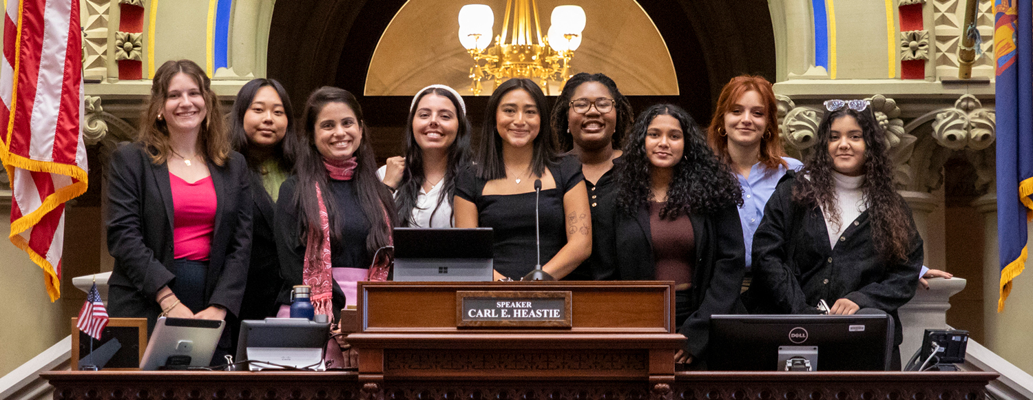 A group of 9 women pose in the New York State Capitol.