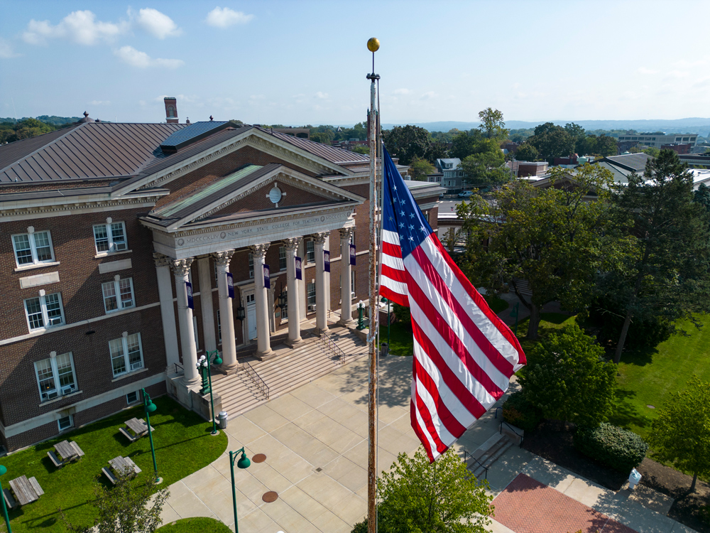 The UAlbany Downtown Campus with a U.S. flag in the foreground.