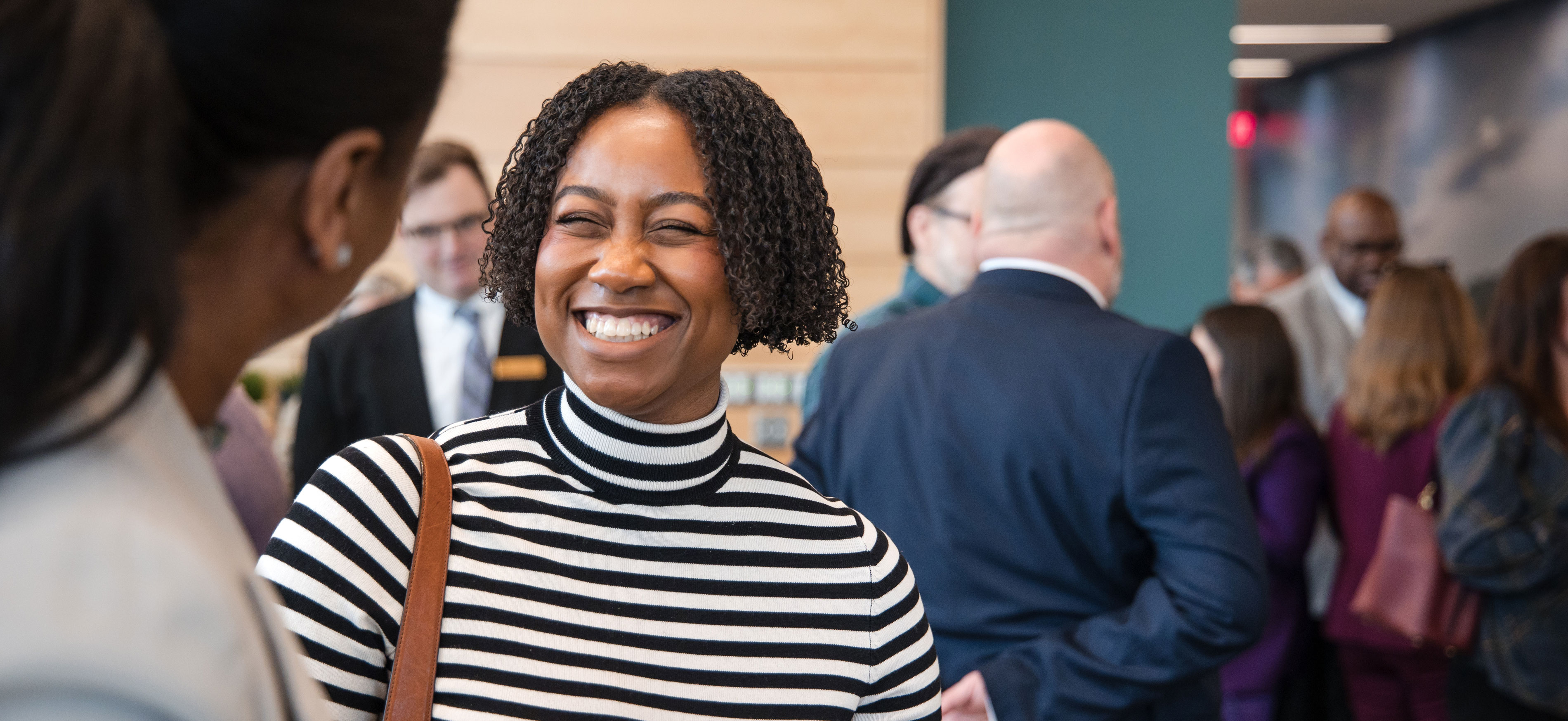 A University employee smiles while speaking to another person.