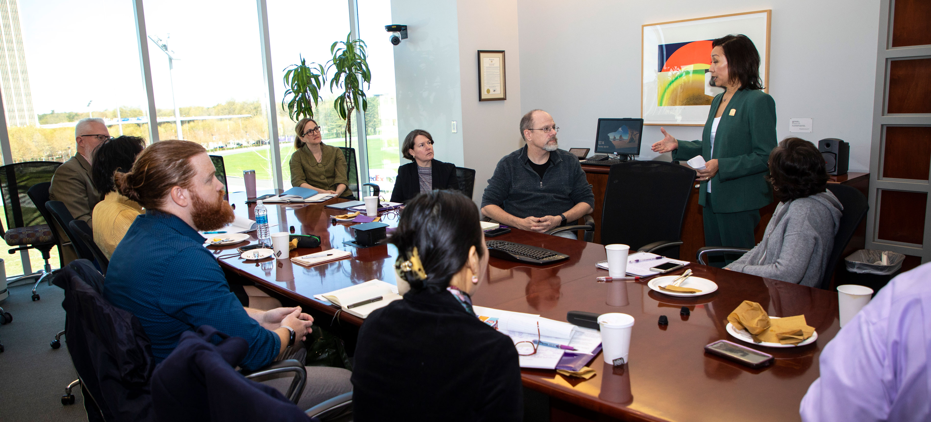 Provost Carol Kim speaks to nine faculty members seated at a conference table.