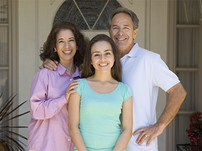 A family smiles for a photo at the front door of their house.