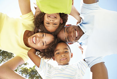 A family of four with smiling faces looking down.