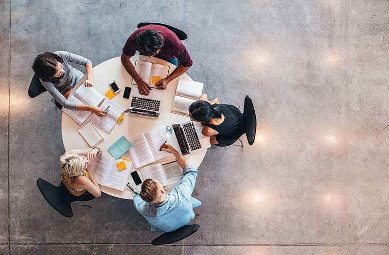 Five people working at a table together.