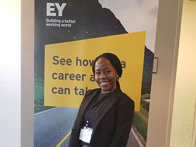 Lesanne grant poses for a photo in front of an EY poster