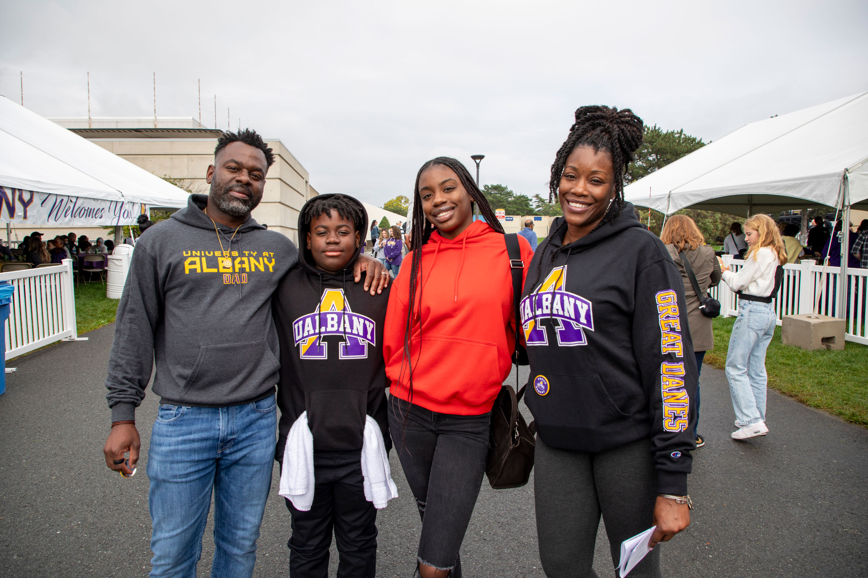 Four family members wearing UAlbany sweatshirts smile and pose for a photo during Great Dane Family Weekend.