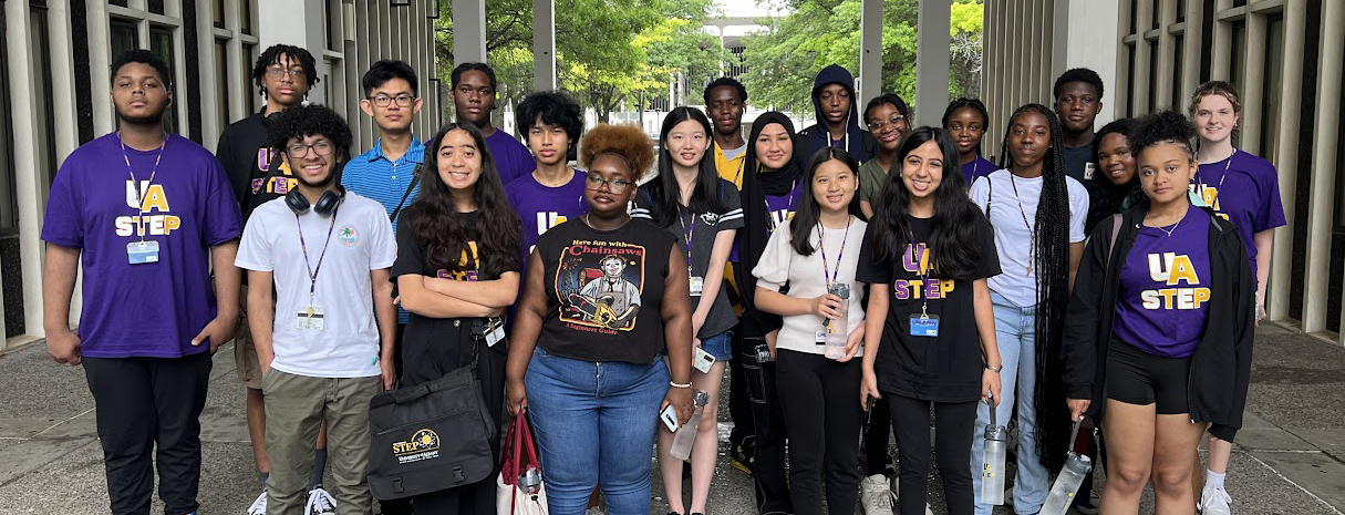 About 20 students participating in UAlbany's Science & Technology Entry Program (STEP) pose for a photo outside on campus.