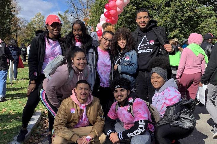 Group of students flanked by pink, red and white balloons.