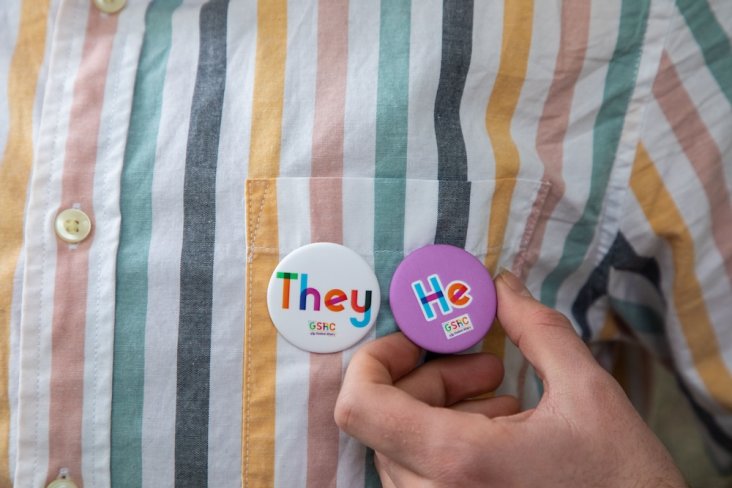 Multicolored shirt with pronoun pins attached.