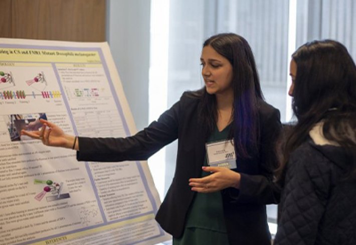 A high school student shows off their research poster at UAlbany.