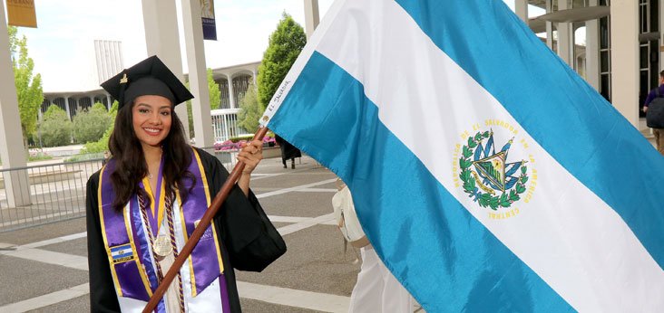 Student holding her country's flag at commencement.