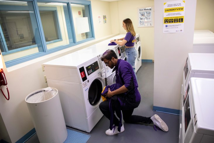 Two students do laundry inside a residence hall laundry room.