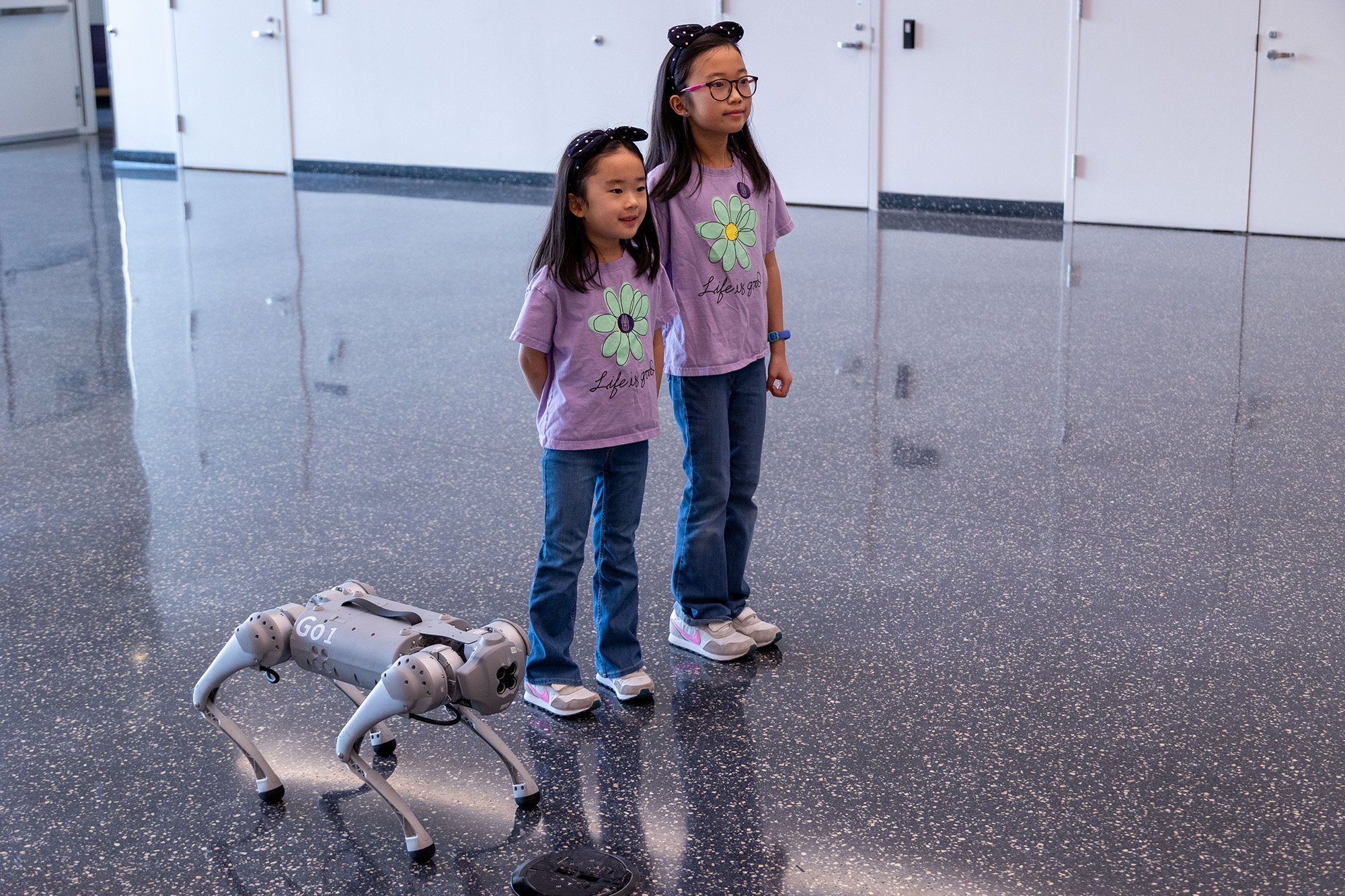 Two young girls stand next to a robot dog at UAlbany's STEM & Nanotechnology Family Day at ETEC.