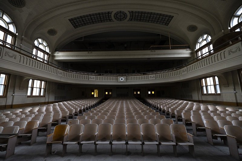 A photo of an unrenovated, century-old three-level auditorium taken from the stage facing the seats.