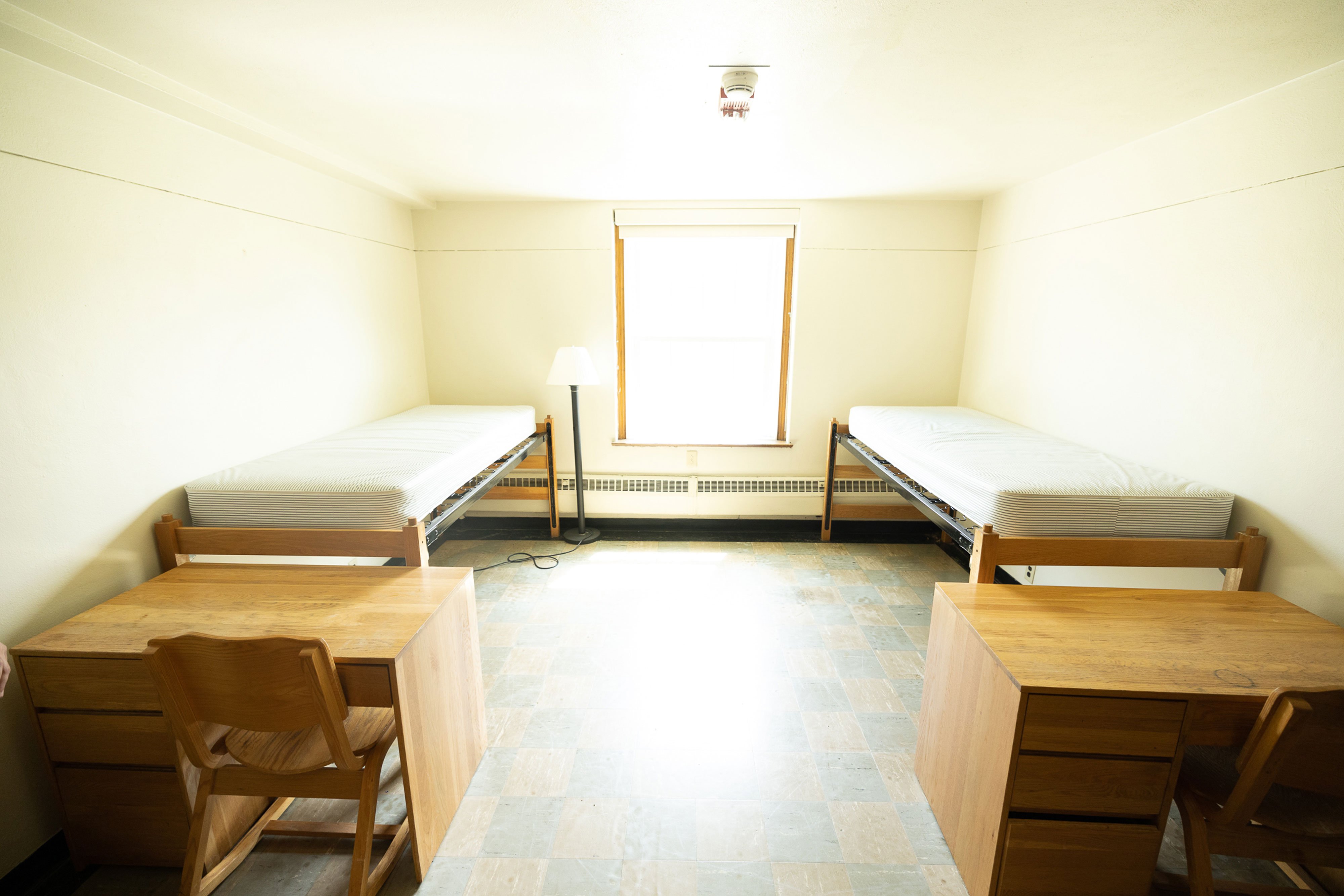 A double bedroom inside Alumni Quad, with two twin beds, two desks and two chairs.