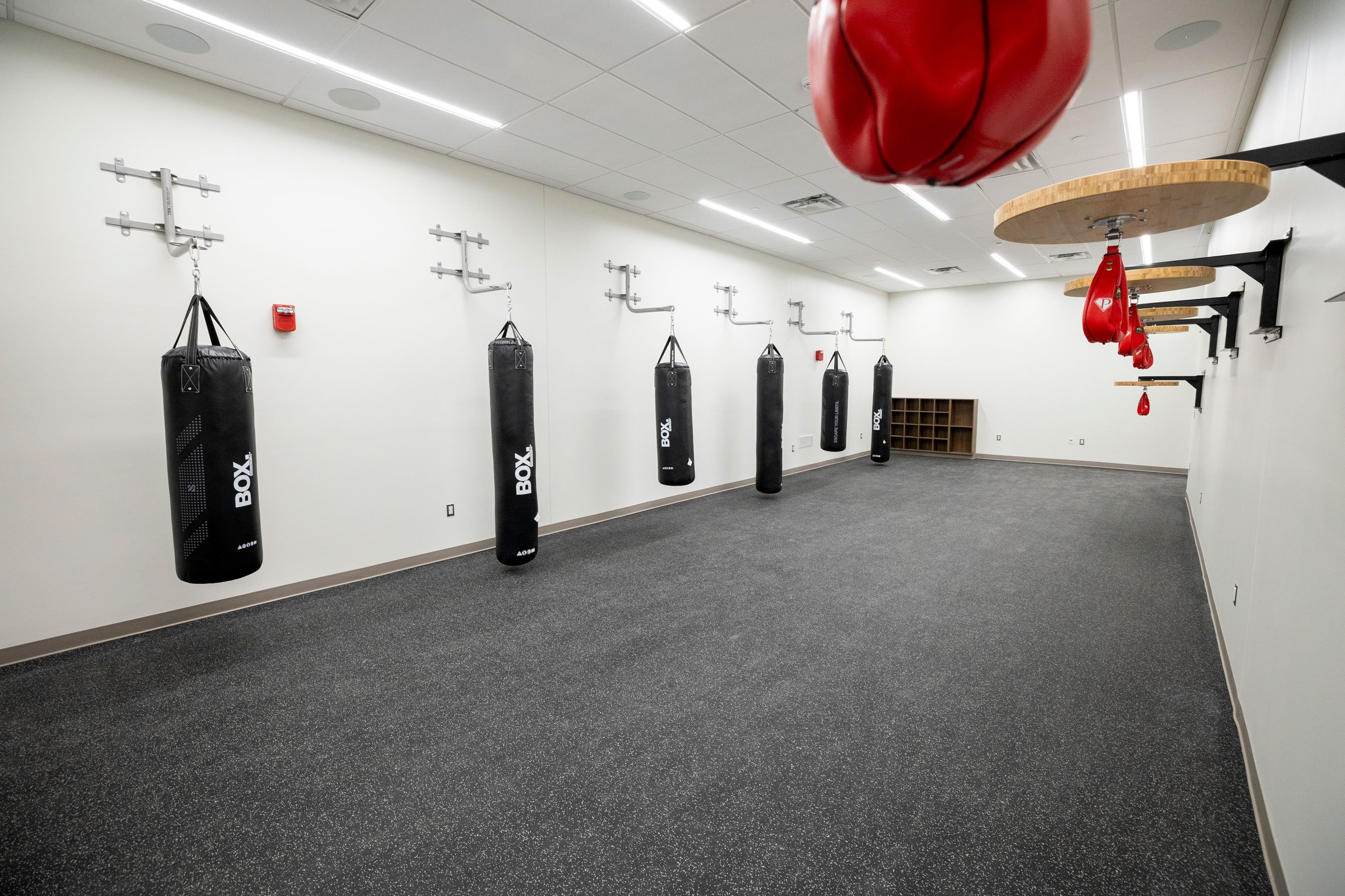 A group exercise room with boxing and kickboxing equipment, such as speed bags and punching bags.