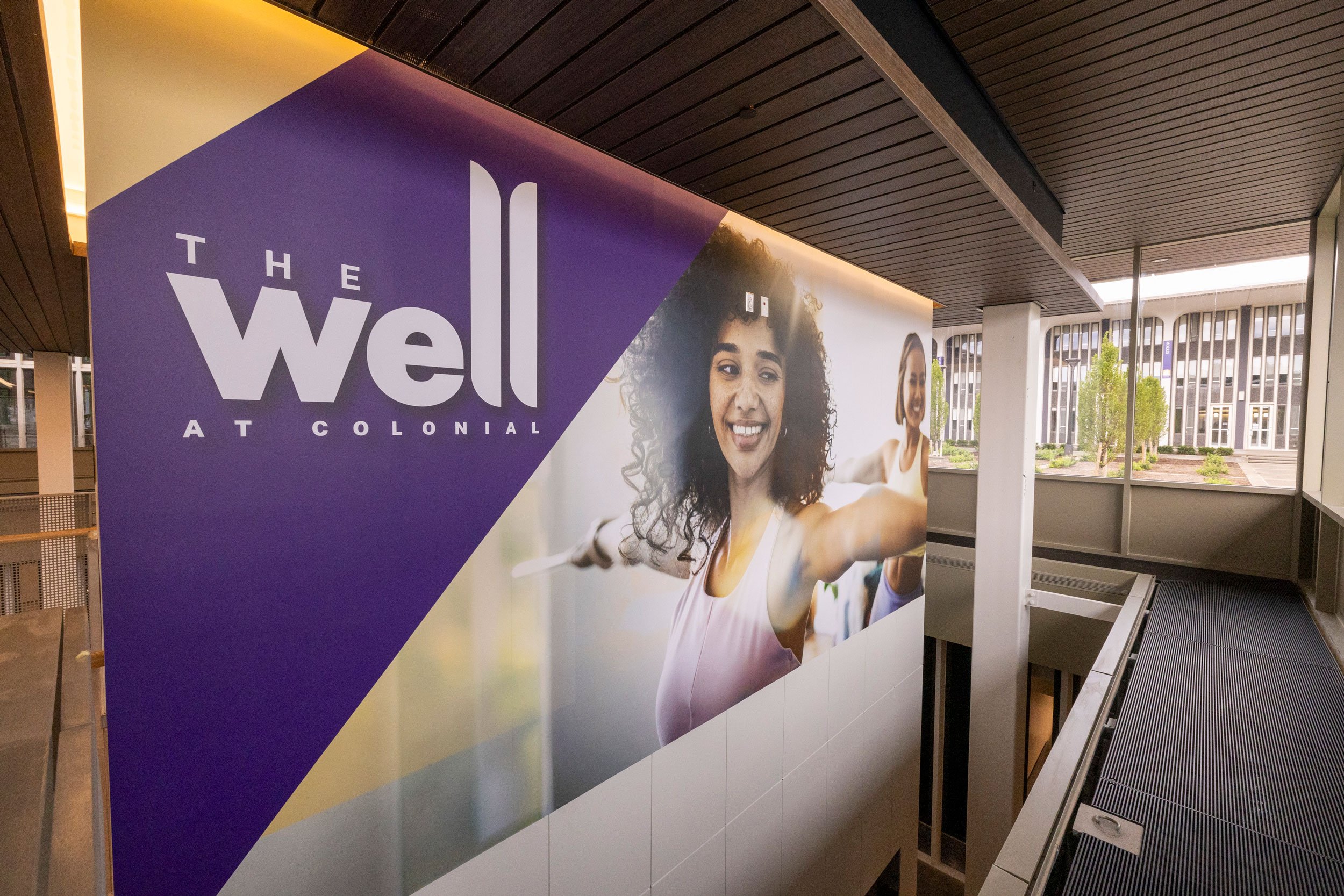 A large sign that says The Well at Colonial and features a smiling woman in a yoga pose.