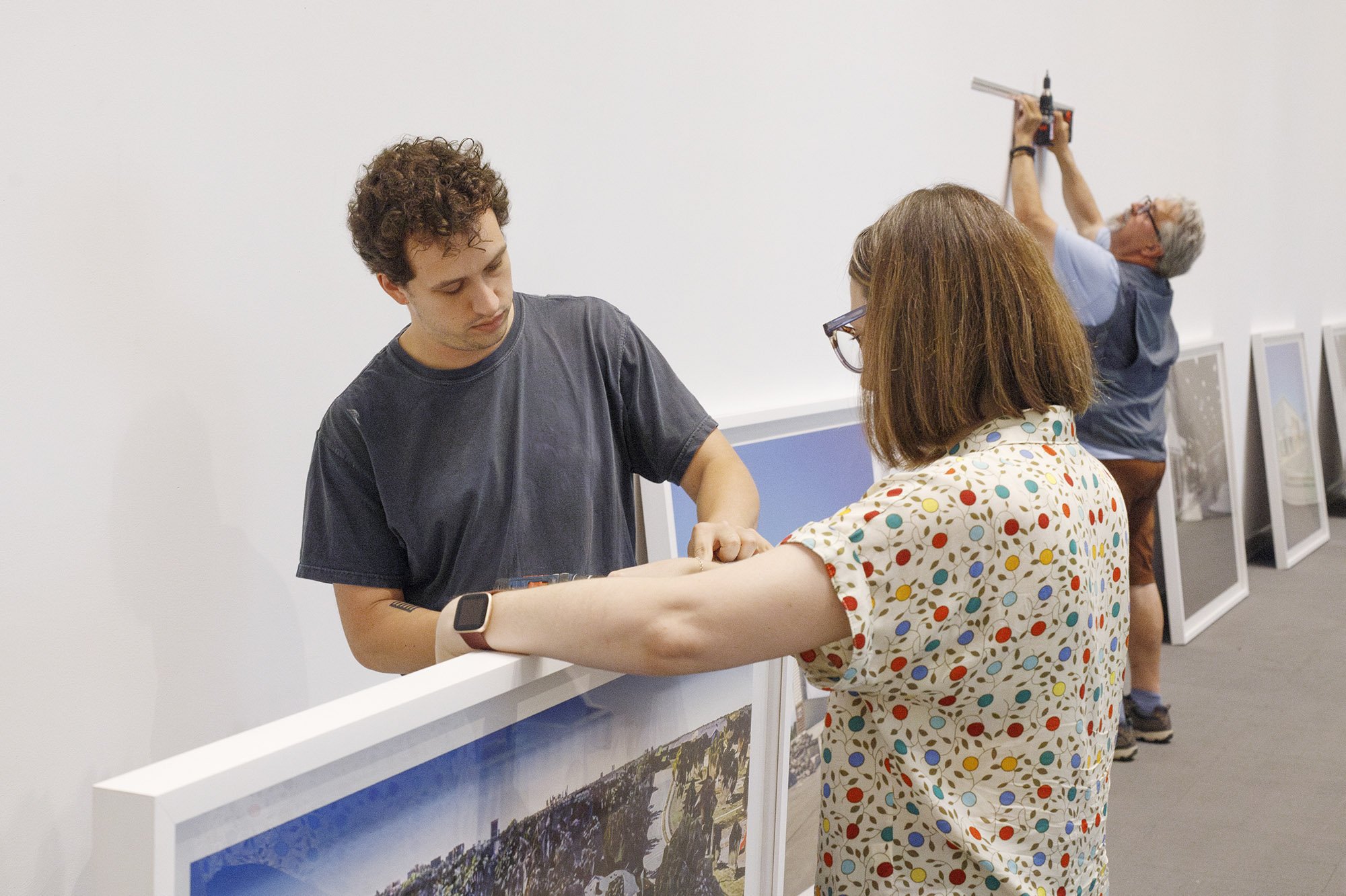 Museum staffers installing framed photographs