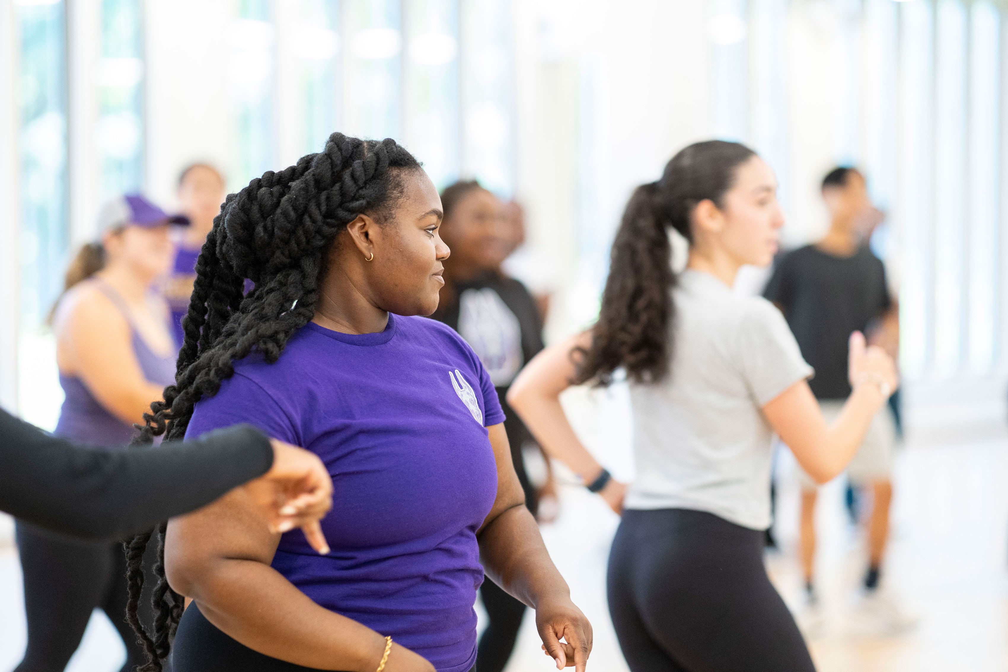 Students twist their torsos while following along in a group dance class.