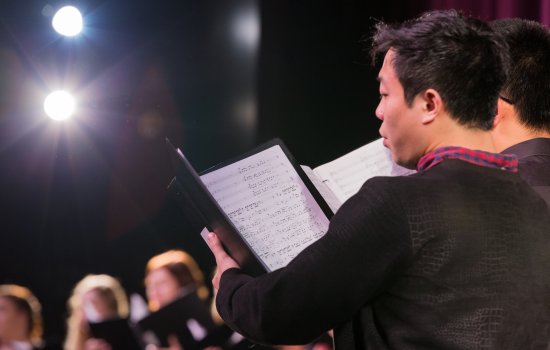 vocalist stands on stage with sheet music during concert