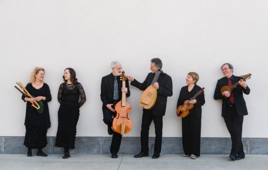 six musicians pose against a wall with their instruments