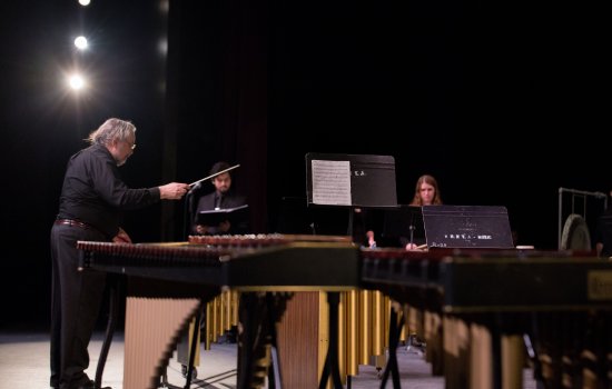 percussionists play music on stage with conductor