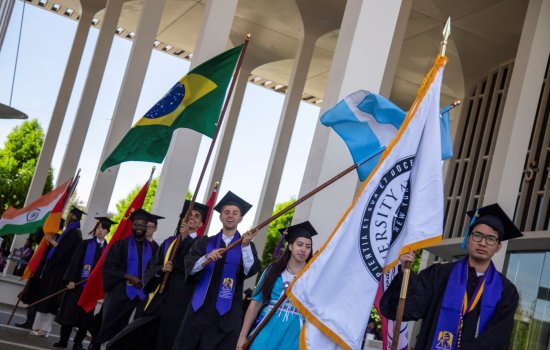 International students carrying flags from their countries at Commencement